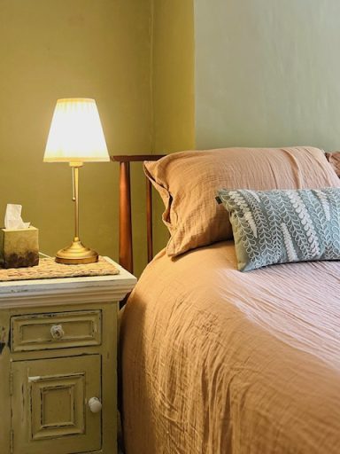 Bedroom One Cozy bedroom with a bed, decorative pillow, and a bedside lamp on a small table.